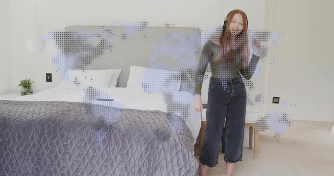 Woman tapping headphones and moving to music by bed, technology dotted world-map overlay responding
