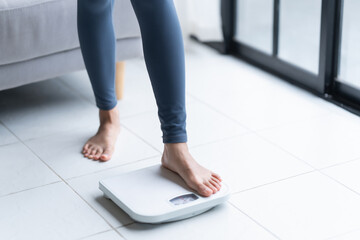 Fat diet and scale feet standing on electronic scales for weight control. Measurement instrument in kilogram for a diet control.