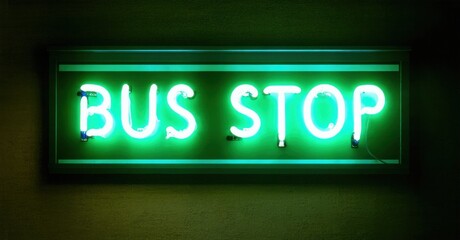 Obraz premium Bright green neon sign displays BUS STOP. Dark background emphasizes glowing text. Simple rectangular shape, nighttime scene.