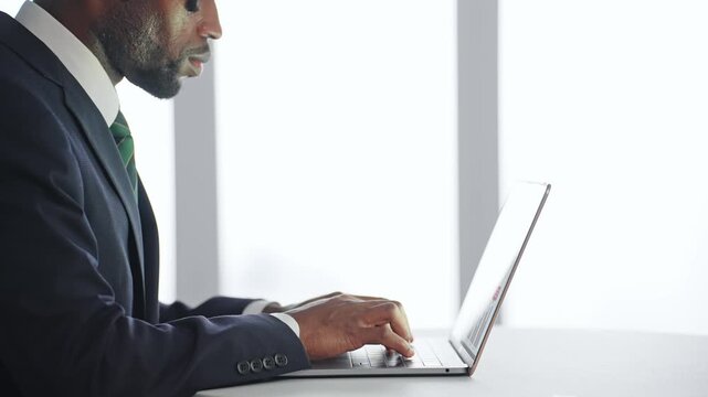 オフィスのデスクでノートPCを使って作業する黒人男性ビジネスパーソン