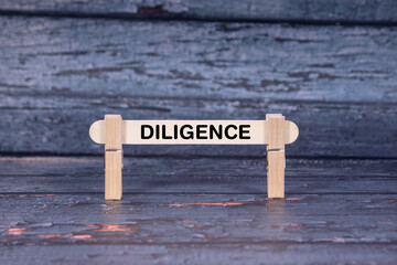 Fototapeta premium Diligence symbol. Wooden stick fastened by Clothespins, A lightly orange toned grunge wooden background. Business and Diligence concept with copy space