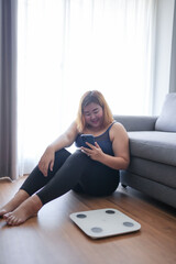 Obese asian woman dieting Weight loss in sportswear using smart phone&nbsp;after workout for weight control at home wellness health.