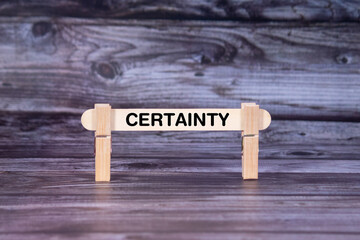 Fototapeta premium Certainty symbol. A wooden stick secured by Clothespins set over beautiful Realistic Wooden Texture Background. Business and Certainty concept with copy space