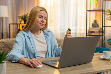 Woman clicks purchase at home, moving items to cart and typing credit card data on laptop with...