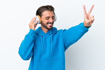 Naklejka premium Young caucasian man isolated on white background listening music and singing