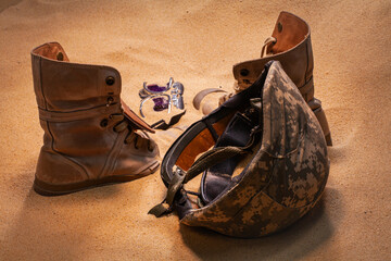 Scattered on the sands of time, the soldier’s gear stands as a tribute to bravery and loss, blending with the desert wind that carries forgotten echoes of war. Silent Memories of War. © Narong Niemhom