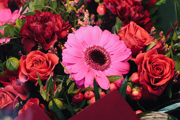 Fototapeta premium Colorful flower bouquet closeup with pink gerbera and red roses. Fresh floral arrangement detail. Romantic gift and celebration concept. Love and beauty in vibrant natural composition.