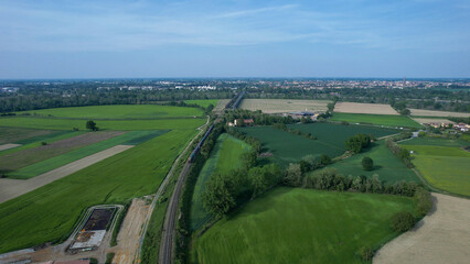 Obraz premium Aerial view of a train traveling through green agricultural fields in the Po Valley, Italy