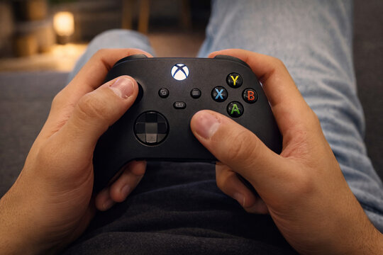 Joueur tenant une manette de jeu vid&eacute;o de marque Xbox, moment de d&eacute;tente &agrave; la maison