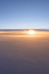 Fototapeta premium The sun above the clouds is a beautiful sunset, an evening cloudy skyscape background, a photo from the window of an airplane flying over the clouds. High quality photo