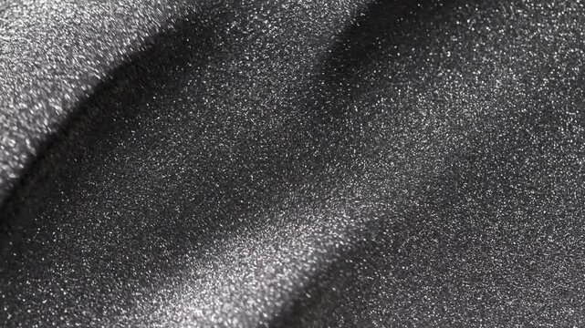 Spinning close-up of dark titanium paint specialized sandy texture and radiant glitter particles on surface