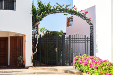 Beautiful metal gates with an arch of flowers.