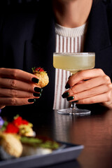 Elegant Woman Holding Classic Margarita and Gourmet Appetizer in Restaurant