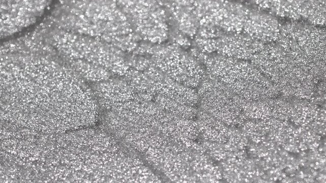 Close-up of bright titanium paint specialized sandy texture and radiant glitter particles on surface