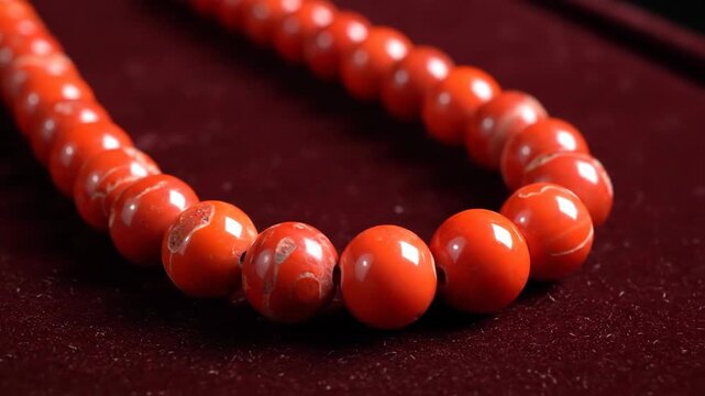 Close Up of Glimmering Red Coral Beads Necklace on Dark Velvet Background