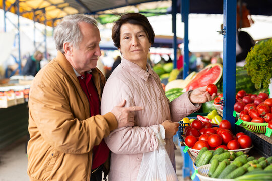 elderly man and woman buy tomatoes at an open market