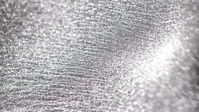 Abstract view of silver titanium paint waves rolling and undulating slowly highlighting glittering particles and elegant texture