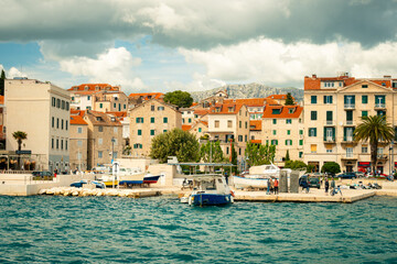 Naklejka premium Sunny Seaside Promenade, Coastal Harbor With Quaint Village, Gentle Waves Lap Against Historic Marina
