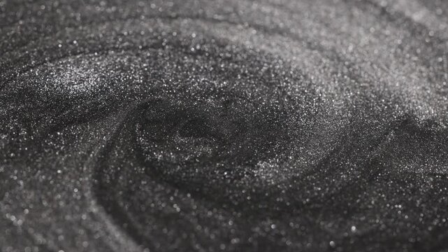 Detailed close-up of dark titanium paint swirling continuously into a deep vortex shape while highlighting specialized sandy texture and radiant glitter particles on the surface