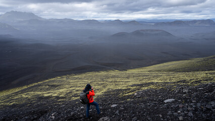 Obraz premium Hiker photographing vast desert like volcanic landscape covered by black sand, Highlands, Iceland