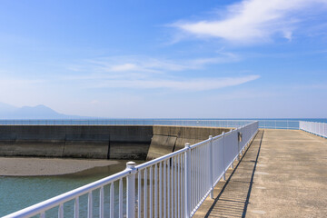 Obraz premium 青空を背景に 「潮風が運ぶ、防波堤から見える海と遊歩道」 宇土市観光スポット(宇土マリーナおこしき館) With a blue sky as a backdrop 