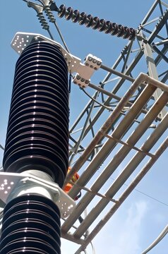 A high-angle, close-up shot of a high-voltage electrical insulator and substation infrastructure.