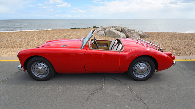 Classic Red MGA  Car  parked on seafront promenade with sea in background.