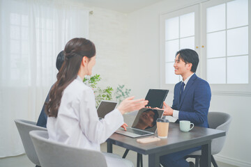 Obraz premium クリニックの会議室で打ち合わせをする若い医師とビジネスマン