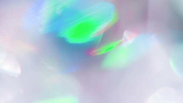Iridescent Bokeh on a Bright Background. Loop. The light passes through the facets of a slowly rotating diamond and creates repetitive sparkling highlights and rainbow colors