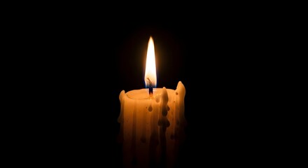A single candle flame illuminated against a dark background
