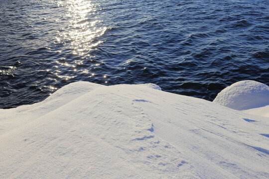 Fresh snow and cold dark blue lake called M&auml;laren or Malar. J&auml;rf&auml;lla, Stockholm, Sweden. Winter day by the sea.