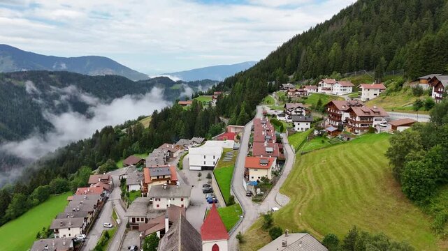 Forward drone flight, cinematic, bird view in small Italian town in the mountains, town Eores (Afers) near Bressanone (Brixen). Cloudy summer day. Charming mountain village in South Tirol, Italy.