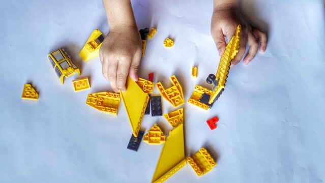 Close up of child's hands playing with colorful plastic bricks. Toddler having fun and building out of bright constructor bricks. Development toys