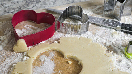 Baking heart cookies with dough cutters and flour
