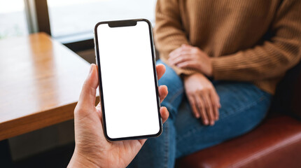 A person holding a modern smartphone with a black screen displaying abstract light patterns while another person sits nearby in a cozy setting mobile phone technology