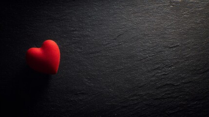 Obraz premium devotion. Minimalist red heart on a textured black surface, symbolizing love and gratitude. wellbeing guides, coaching materials, designed for mental health education and mindfulness programs. 