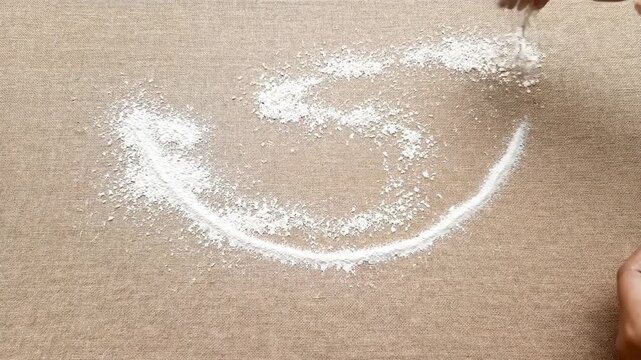 Hand Sprinkling White Powder to Create Intricate Design on Wooden Surface