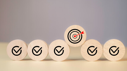 Wooden round blocks with check marks and target icon represent goal achievement, strategic business planning, task management, and checklist success in organizational execution.