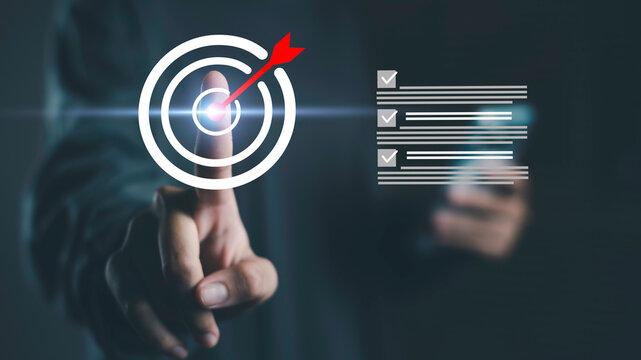 Target with checklist and businessman pointing at center represents goal setting, strategic planning, and achieving business objectives with focus and direction toward long-term success.