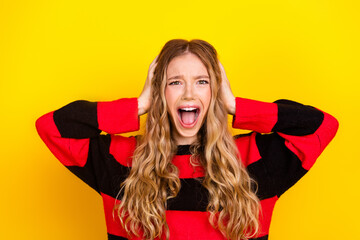 Cheerful young female in stylish striped sweater posing against vibrant yellow background...