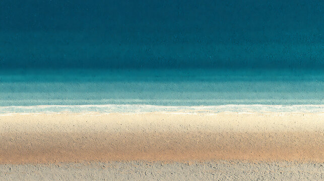 Pristine aerial view of the ocean meeting the shore, showing the vibrant turquoise gradient transitioning into deep azure water and warm beige sand.