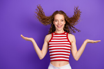 Young woman with red hair striped top smiling against purple background in a playful pose