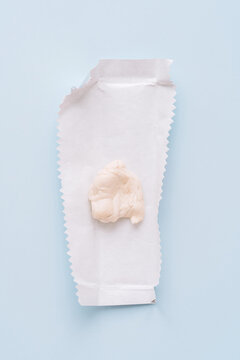 Chewed chewing gum on opened wrapper on blue background, minimal flat lay. High quality photo