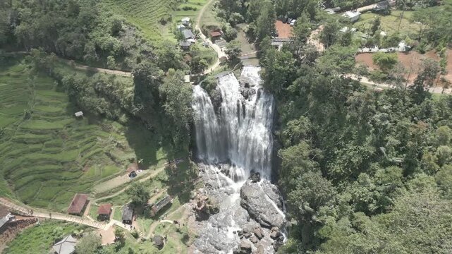 Flat log profile drone shot of Curug Cikondang waterfall in Cianjur, Indonesia, zooming out to reveal lush surroundings