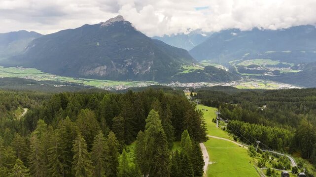 22 july 2024, Imst, Austria. Forward drone flight at ski slope in summer, view on Imst city in Gurgeltal valley and Tschirgant mountain in background. Cloudy summer day. Beautiful travel destination. 