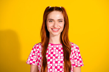 Obraz premium Young woman with red hair in checkered pink and white top smiling against yellow background lifestyle fashion portrait