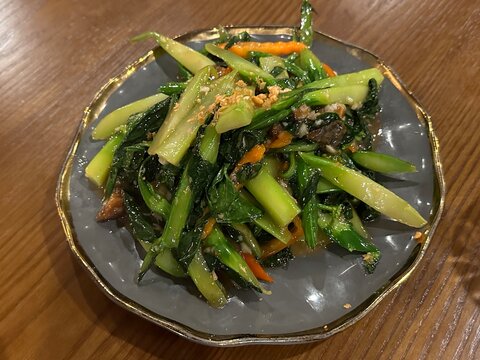 A vibrant stir-fried Chinese Kale dish featuring green leafy greens, served in an elegant gray plate