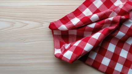 Obraz premium Red and White Checkered Tablecloth Draped Elegantly on a Light Wooden Surface for Cozy Dining or Picnic Themes