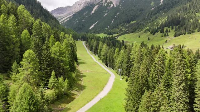 22 july 2024, Imst, Austria. Backward drone flightn reveal at ski slope in summer, beautiful fresh green meadows, pristine alpine pine forest trees during summer day. Hiking trail. Outdoors, nature, e