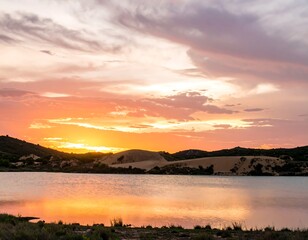 Obraz premium A serene waterscape captures the vibrant hues of a breathtaking sunset, casting a golden reflection across the calm lake